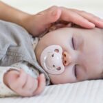 Hand of mother caressing baby girl sleeping